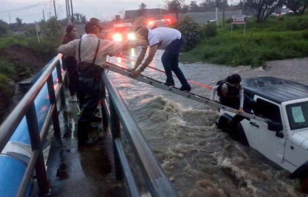 Bomberos rescatan a personas de auto varado en corriente de agua